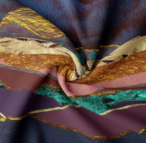 Close-up of smooth silky fabric with artistic purple and gold abstract mountain patterns