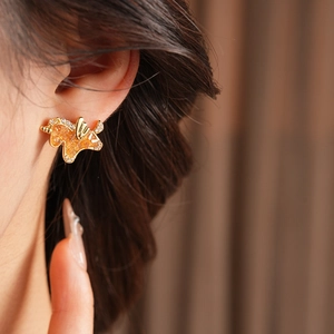 Detailed close-up of golden butterfly earrings with orange gems on a model ear