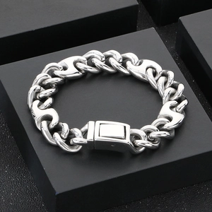 Macro detail of silver stainless steel Cuban link bracelet with H-shape clasp on a stand