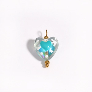 Macro detail of a cyan heart-shaped glass pendant with gold loop for DIY jewelry making