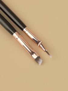 Close-up of dual-ended eyebrow and eyeliner brushes with rose gold metal ferrules