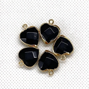 Detailed view of five black heart-shaped stone pendants with gold-plated metal borders