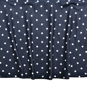 Close-up detail of dark blue fabric with white polka dots and stitched hemline texture