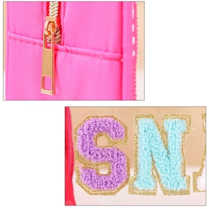 Detail of pink fabric makeup bag with golden zipper and chenille letter patches