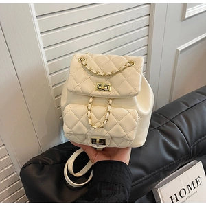 Detail of beige quilted mini backpack featuring gold turn-lock and leather chain strap