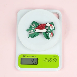 Gros plan d'une pince à cheveux de 4,7g avec ruban Joyeux Noël et bonnet de Noël