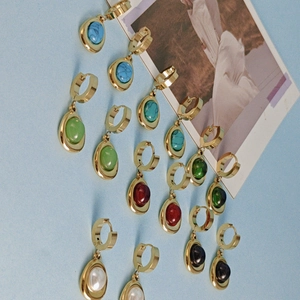 Golden drop earrings set with colorful gemstones and pearls on light blue background