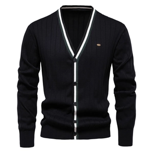 Dettaglio del cardigan con scollo a V e finiture a righe bianche e verdi su maglia nera