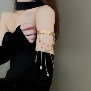 Detail view of a gold-plated arm cuff featuring star heart tassels and metallic chains