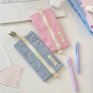 Detailed shot of pink and blue fabric pencil cases with silver stars on a desk