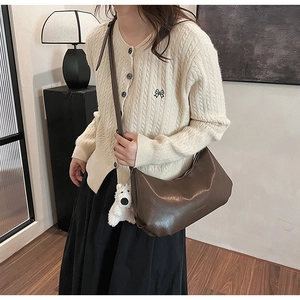 Detail of dark brown crescent PU leather bag with cute white dog plush pendant charm