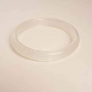 Macro detail of translucent white cat eye stone bangle with smooth polished finish