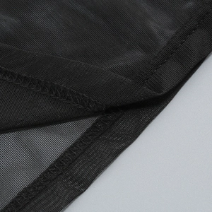 Détail macro du tissu en maille noire avec couture surjetée fine et texture semi-transparente