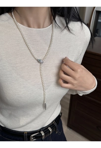 Detailed view of elegant pearl necklace with crystal snake head charm on light knit sweater