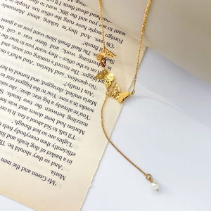 Detail of golden butterfly necklace with pearl pendant on vintage book background