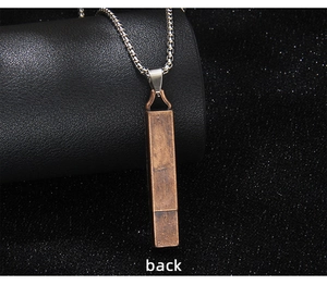 Macro detail of vintage bronze whistle pendant with metallic box chain texture