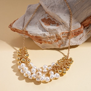 Detailed view of baroque cluster pendant with faux pearls and golden beads on rock