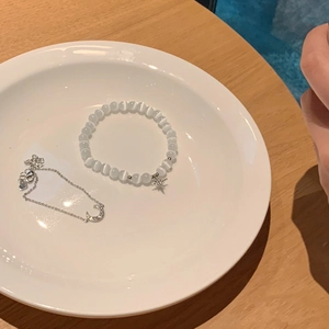 Detalle de pulsera de opalo con estrella y cadena de luna en un plato de cerámica