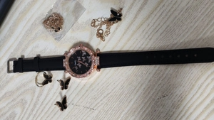 Detailed set of rose gold butterfly watch, leather strap, bracelet, ring, and earrings