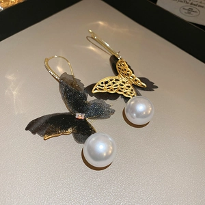 Close-up of asymmetric butterfly earrings with black mesh wings and white pearls