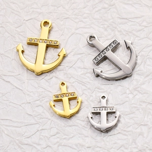 Detailed view of gold and silver anchor pendants with crystal accents on textured background