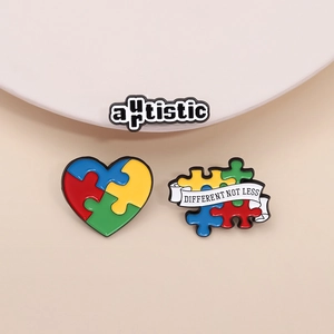 Three colorful autism awareness enamel pins with heart puzzle and Different Not Less text