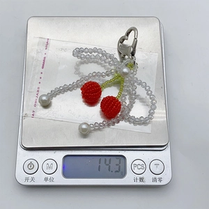 Detail shot of crystal cherry keychain on digital scale showing its weight of 14.3 grams