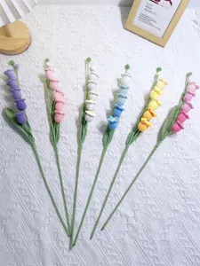 Flat lay of handmade crochet lily of the valley bouquets in six vibrant colors