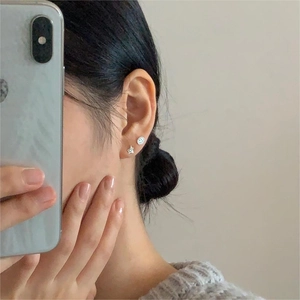 Detailed close-up of S925 sterling silver star and smiley face hoop earrings on model