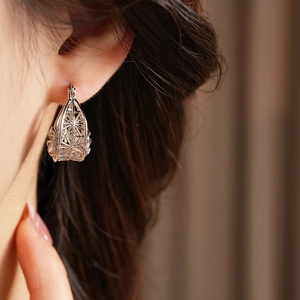 Close-up of a silver hollow teardrop earring worn by a model showcasing metallic texture