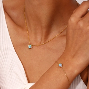 Close-up of gold-plated necklace and bracelet set featuring teardrop opal pendants on model