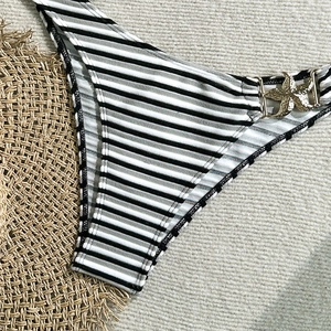 Detail of striped bikini bottom featuring fine ribbed texture and golden starfish buckle