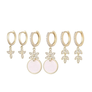 Detail of three pairs of gold earrings with star pendants and white zircon stones
