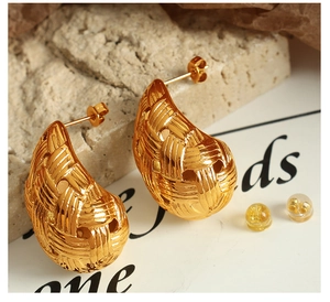 Macro detail of gold plated teardrop earrings with textured woven pattern on stone