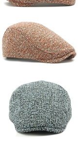 Close-up detail of vintage tweed wool flat caps in orange-brown and blue-grey textures