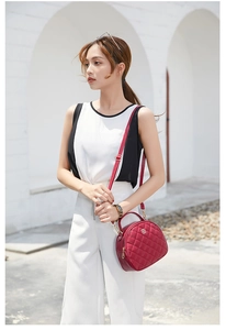 Detail of red quilted semicircular crossbody bag with chain strap and metal clover