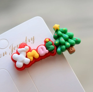 Detailed view of a green Christmas tree hair clip with festive colorful Xmas lettering