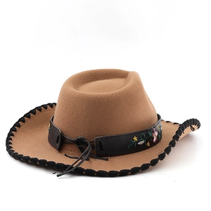 Detail of tan cowboy hat with black braided trim and floral embroidered leather band