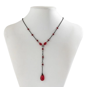 Detail of gothic Y-shaped necklace with black chain and faceted red crystal teardrop