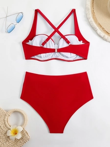 Flat lay of red bikini set with cross back top, high waist bottoms and summer accessories