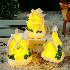 Close-up of lighted miniature resin Christmas houses with warm LED snow landscape details