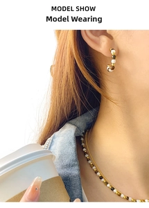 Detail of C-shaped tiger eye stud earrings and necklace set shown on a model