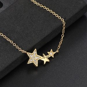 Macro shot of three gold star pendants with sparkling zircons and polished finish