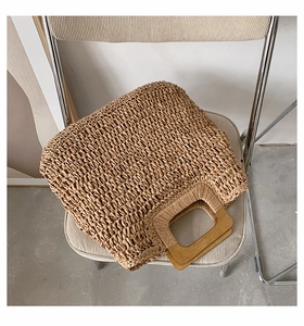 Close-up of handwoven straw tote bag with wooden handles on a minimalist chair