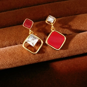 Macro shot of asymmetrical 18k gold plated diamond earrings with red and white zircon detail