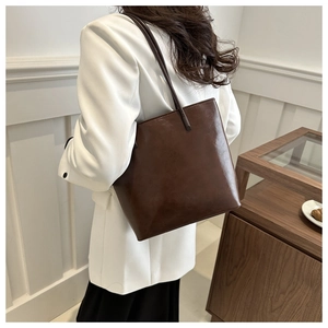 Detail shot of a dark brown large tote bag worn with a white blazer for a chic look