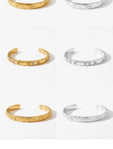 Macro detail of stainless steel cuff bracelets with sun, moon, and star patterns