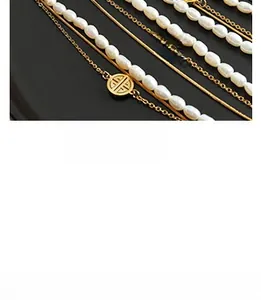 Detailed close-up of layered 18K gold-plated snake chains and irregular white pearl necklaces