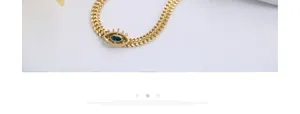 Macro view of gold snake chain necklace featuring a blue evil eye pendant with metal rays