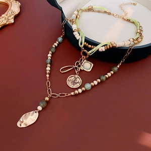 Close-up of bohemian layered beaded necklace with butterfly pendant and metal leaf charms